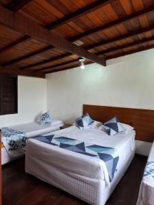 Un dormitorio con dos camas y techo de madera. en Lua Chalés 14 chalés equipados com churrasqueira individua , piscina e hidro incluindo café da manhã servido no quarto , roupa de cama, toalhas de banho e de praia a apenas 600 metros da praia de Maresias, en Maresias
