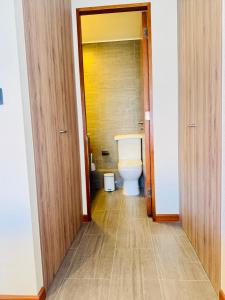 a bathroom with a toilet and a wooden door at Departamento en Península in Iquique +4 photos