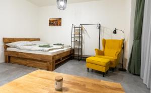 ein Schlafzimmer mit einem Bett und einem gelben Stuhl in der Unterkunft Apartmán Jizera in Jablonec nad Nisou