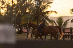 Ein Mann reitet auf einem Pferd im Sonnenuntergang in der Unterkunft Hotel Fazenda Monte Castelo in Bezerros