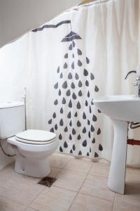 un bagno con un water, un lavandino e una tenda da doccia di Desert Tracks Rancho a Las Grutas