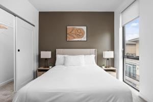 una camera da letto con un grande letto bianco e due finestre di Super LUX SkyTower 2BD Downtown - Parking, Pool, Gym a Indianapolis Altre 31 foto