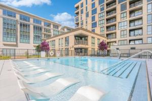 una piscina con sedie a sdraio bianche di fronte a un edificio di Downtown Townhome Game Room with Pool, Parking, Gym a Indianapolis
