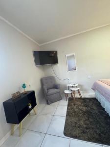 a bedroom with a bed and a chair and a tv at PNZ Loft 2 in Petrolina