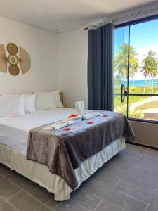 a bedroom with a bed with a view of the ocean at Pousada Canouan in Japaratinga