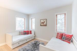 a white room with a couch and two windows at Altitude Ski-in Out at Resort with Private Hottub in Mont-Tremblant