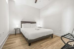 a white bedroom with a large bed and a chair at Chic Channelside Getaway in DT | Close to DT! in Tampa +20 photos