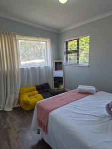 een slaapkamer met een groot bed en een gele poef bij Holland Manor in Durban