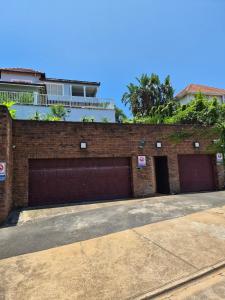 een bakstenen gebouw met twee garagedeuren en een huis bij Holland Manor in Durban