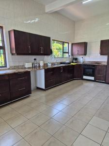 een grote keuken met bruine kasten en een tegelvloer bij Holland Manor in Durban