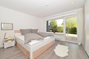 een witte slaapkamer met een bed en een raam bij Haus Ideal 3-Raum-Wohnung edelWEISS in Fischen