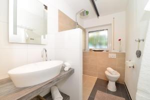 een witte badkamer met een wastafel en een toilet bij Haus Ideal 3-Raum-Wohnung edelWEISS in Fischen