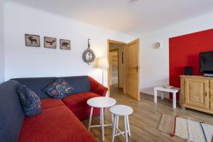 a living room with a red couch and a table at Haus Ideal 2-Raum-Wohnung Rosenrot in Fischen
