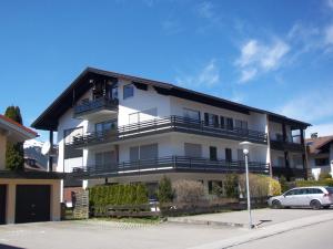 a white building with a car parked in front of it at Haus Ideal 2-Raum-Wohnung Rosenrot in Fischen +4 photos