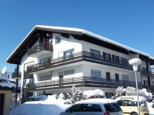 a large white building with cars parked in the snow at Haus Ideal 2-Raum-Wohnung Rosenrot in Fischen