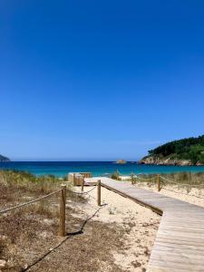 un sentiero in legno per la spiaggia con l'oceano sullo sfondo di Lúa of Livinggaliciabeach a O Vicedo