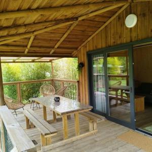 a wooden patio with a table and chairs on a deck at ZEcamping 3 étoiles piscine chauffée in Vendoire