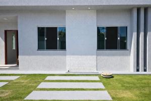 a white house with windows and a grass yard at Casa privativa em Itaúna in Saquarema