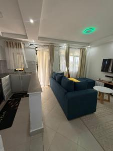 a living room with a blue couch and a kitchen at NikLan Homes in Naivasha