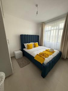 a bedroom with a blue bed with yellow pillows at NikLan Homes in Naivasha
