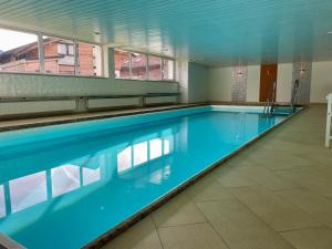 a large swimming pool with blue water in a building at Wohnung BergFrei - mit Hallenbad und Sauna in Bolsterlang