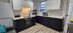 een keuken met zwart-witte kasten en een wastafel bij St Johns - 2 Bed House in Balby