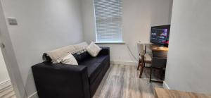 een woonkamer met een zwarte bank en een televisie bij St Johns - 2 Bed House in Balby