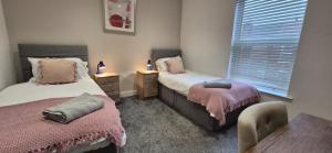 een slaapkamer met twee bedden, een tafel en een raam bij St Johns - 2 Bed House in Balby