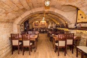 Un restaurante con mesas y sillas de madera en un muro de piedra. en Wine Garden Hotel Comrat, en Komrat