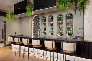 un bar con sedie bianche e bottiglie di vino di JD Village a Itapema