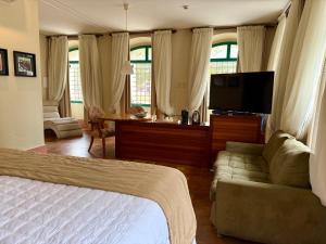 a bedroom with a bed and a couch and a flat screen tv at Atrium Hotel Quinta De Pedras in Belém