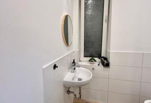 ein weißes Badezimmer mit Waschbecken und Spiegel in der Unterkunft Zentral gelegene Wohnung mit Selbst-Check-in und WLAN in Bielefeld