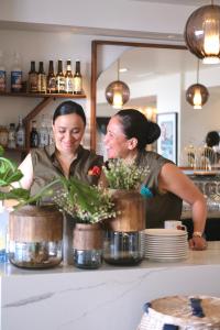 Dos mujeres de pie detrás de un mostrador con flores. en Santateresa, en Bonifacio