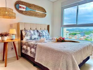 a bedroom with a bed and a large window at Apto 3 Quartos Condomínio Resort Completo Pé na areia com Piscina borda Infinita, Beach Tennis, Academia, Sala de Jogos, Brinquedoteca, Playground e Portaria 24H 2 Quartos com Ar-Condicionado, Churrasqueira Privativa Reserve Agora e Viva essa Experiência in Piçarras