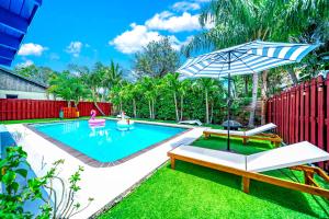 einen Pool mit einem Sonnenschirm und einem Tisch in der Unterkunft Sunset Haven with Saltwater Pool & mins to beach in Delray Beach