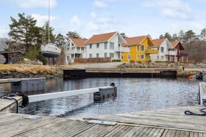 a dock with houses and a boat in the water at Modern Seaside Cabin Tvedestrand Hantho Brygge in Tvedestrand