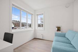 a living room with a blue couch and windows at Modern Seaside Cabin Tvedestrand Hantho Brygge in Tvedestrand