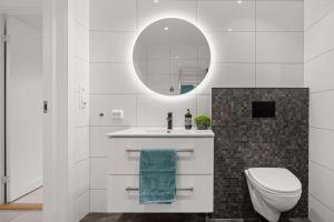a bathroom with a sink and a toilet and a mirror at Modern Seaside Cabin Tvedestrand Hantho Brygge in Tvedestrand +20 photos