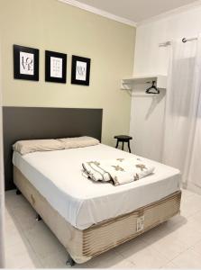 ein Bett in einem Schlafzimmer mit drei Bildern an der Wand in der Unterkunft Bela Casa Em Caldas Novas in Caldas Novas