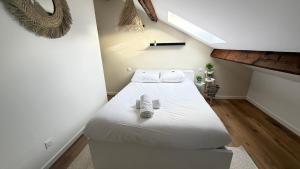 ein Schlafzimmer mit einem Bett mit weißer Bettwäsche und Hausschuhen in der Unterkunft Le Cormontaigne - Metz - 6P in Metz