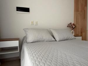 a bedroom with a bed with white sheets and a tv at Departamentosenchascomus in Chascomús