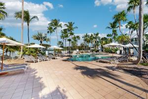 een zwembad met stoelen, parasols en palmbomen bij Jewel in the Sea in Duck Key
