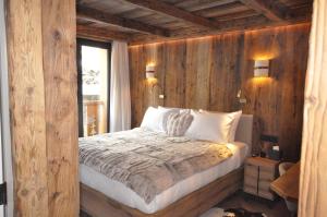 a bedroom with a bed with wooden walls and a window at Hotel Vall d'Isard Suites in El Tarter