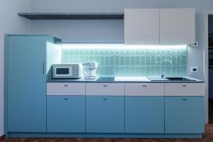 a kitchen with white cabinets and blue lighting at Nidin Apartments in Cassano Spinola