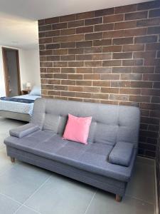 a couch with a pink pillow on it next to a brick wall at Sabaneta, aparta Loft, excelente Ubicacion, Wifi in Sabaneta