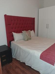 een slaapkamer met een groot bed met een rood hoofdeinde bij Imany house in Kaapstad