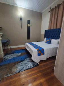 een slaapkamer met een bed met een blauw hoofdeinde en een tapijt bij Imany house in Kaapstad