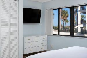 a white bedroom with a tv and a bed at Sabal Palms Inn in St. Pete Beach