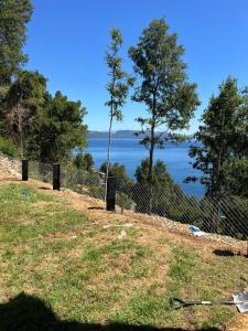 ein Zaun auf einem Hügel mit Blick auf das Wasser in der Unterkunft Increíble casa con vista al lago in Licán Ray