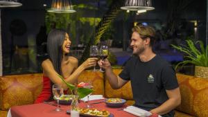 a man and woman sitting at a table drinking wine at Ferraretto Guarujá Hotel & Spa in Guarujá